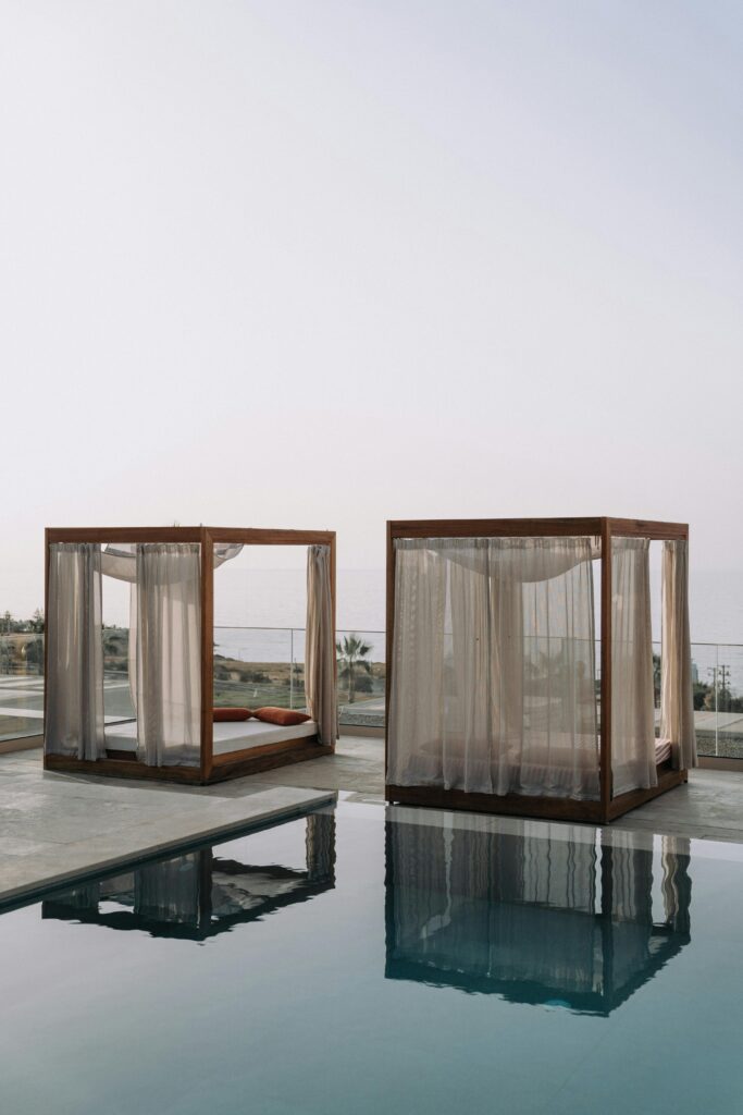 Two stylish cabanas by a serene pool with an ocean backdrop, perfect for a luxurious escape.